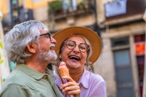 Senior couple laughing and enjoying a refreshing ice cream cone together during a relaxing summer