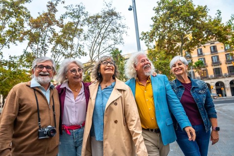 Group of smiling multi ethnic senior friends embracing, walking, and enjoying a sightseeing trip in
