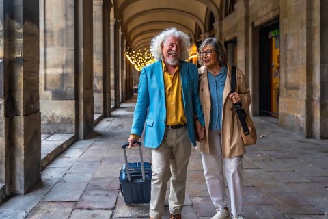 Happy senior couple smiling and holding hands while walking through a european city street, pulling