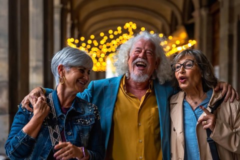 Three laughing senior friends enjoying a lively conversation and close companionship while walking