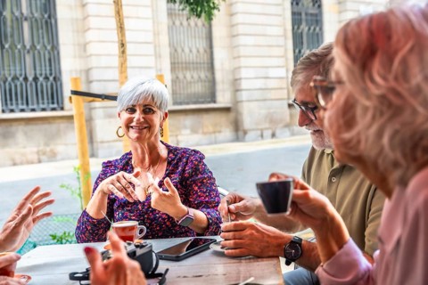 Mature adults gathering socially at an outdoor cafe, enjoying coffee and engaging in lively