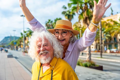 Senior couple enjoying their summer vacation together in a vibrant city, smiling brightly and