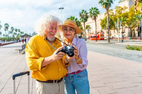 Happy senior couple exploring a sunny european city, smiling as they review photos on a vintage