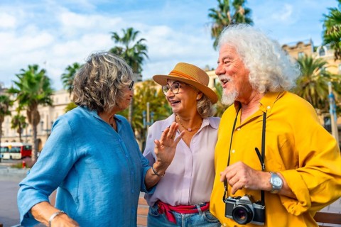 Three cheerful senior friends enjoying a lively discussion outdoors during their city vacation,