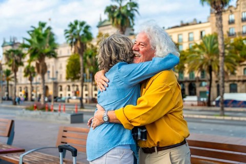 Enthusiastic senior couple embracing each other with joy and affection in a city setting, enjoying