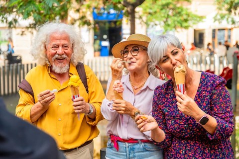 Group of happy senior friends smiling and eating ice cream cones outdoors, enjoying summer day and