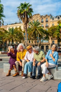 Group of happy senior friends enjoying their city vacation, sitting outdoors and laughing together