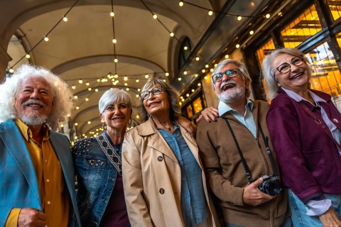 Group of happy senior friends smiling while walking together in a city street at night,