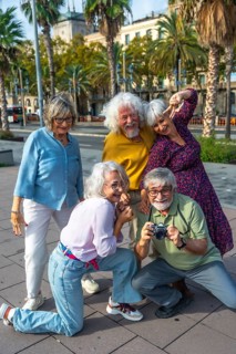 Cheerful group of senior friends traveling together, capturing fun memories with an analog camera