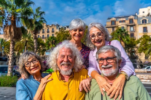 Happy multiracial senior friends smiling and embracing on a sunny city street during vacation,