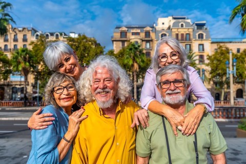 Smiling group of senior friends enjoying carefree retirement travel together in a sunny european