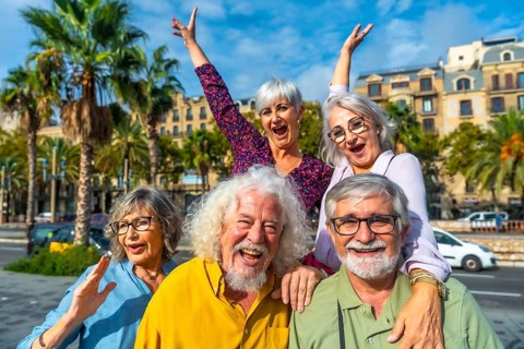 Happy senior friends smiling and raising hands, celebrating friendship and active retirement during