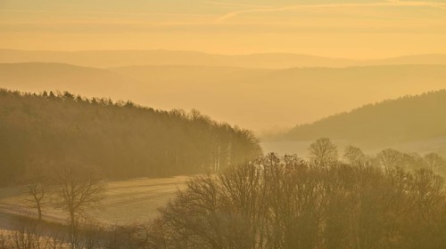 Blurred hills and golden sky at sunrise create a misty, quiet landscape, Seckmauern, Lützelbach,