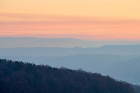 Pastel-colored silhouettes of hills and trees at sunset convey a peaceful atmosphere, Seckmauern,
