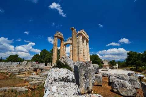Ancient remains and columns surrounded by large stones under a cloudless sky, Nemea, Ancient Zeus