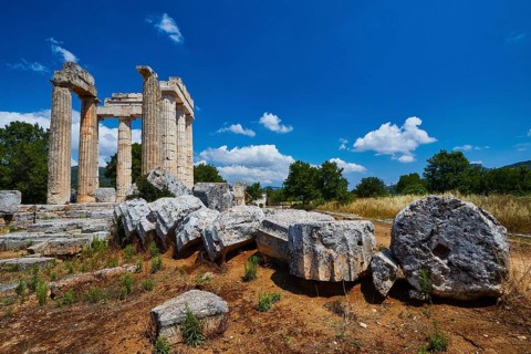 Stone columns and fragments against a clear blue sky in an open landscape, Nemea, Ancient Zeus