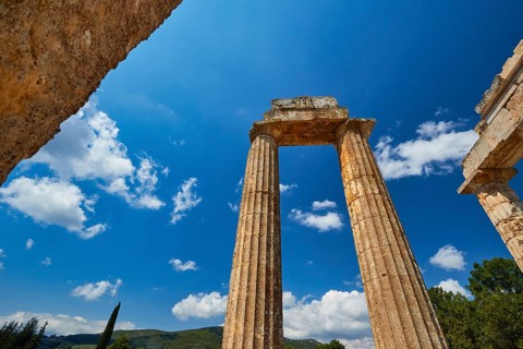 Massive ancient pillars rise against a bright blue sky, Nemea, Ancient Zeus Church, Archaeological