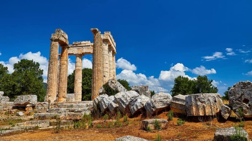 Ancient columns and ruins with loosely scattered stones in the foreground, Nemea, Ancient Zeus