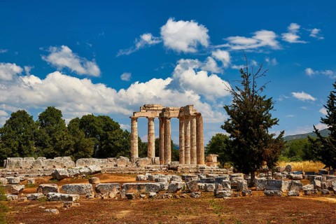 Stone ruins and ancient pillars against a cloudy blue sky, Nemea, Ancient Zeus Church,