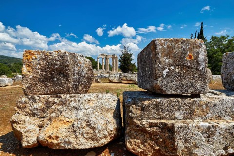 Ancient ruins with large stones against a bright blue sky with clouds, Nemea, Ancient Zeus Church,