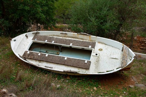Old rowing boat lying abandoned in an olive grove, Majorca, Spain