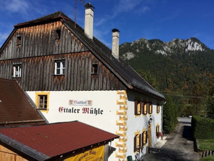 View of side view of Gasthof Ettaler Mühle in a historic two-storey baroque half-hipped roof dating