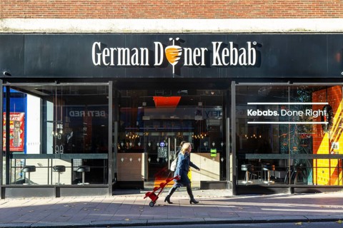 Person passing GDK German Doner Kebab takeaway restaurant in city centre, Exeter, Devon, England,