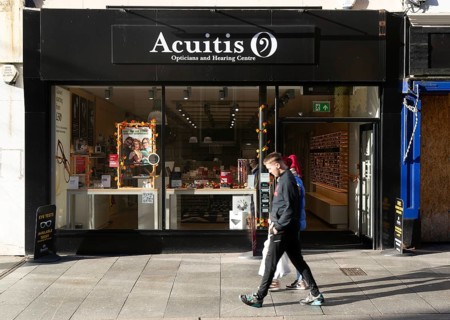 Shoppers passing Acuitis opticians and hearing centre shop store, High Street, Exeter, Devon,