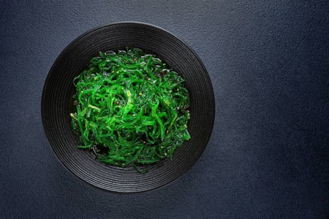 Chuka salad, made from fresh seaweed, with sesame dressing, served in a black bowl