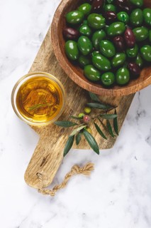 Chalkidiki olives, classic Greek green olives, in a bowl on a cutting board, top view, without