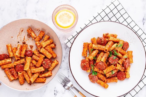 Rigatoni pasta with spicy sausage, and rich tomato sauce served, on a white plate, homemade