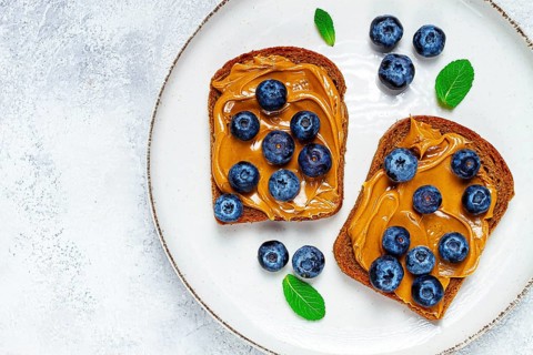 Rye bread with peanut paste and fresh blueberries, top view, no people
