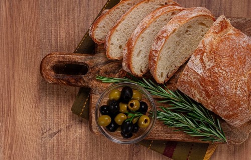 Sliced ciabatta, on a chopping board, with rosemary and olives, Italian bread, close-up, Italian