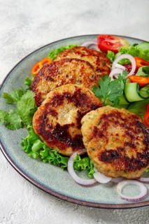 Fried chicken cutlets, minced chicken, with vegetables, on gray, with vegetable salad, top view,