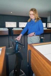 A woman wearing a blue shirt interacts with a screen in the museum, robotic personality