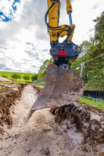 Close-up of an excavator digging a deep ditch, construction of a PV freeway plant, Weil der Stadt,