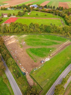 Aerial view of a green landscape with tennis court and surrounding trees, PV Freifaechenanlage