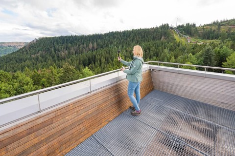 Individual taking photos of an elevated platform with a view of wooded hills, Ruhestein National