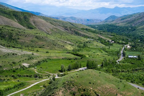 Green fields and rolling hills with roads leading through the area, under clear skies, countryside