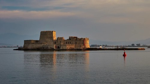 Bourtzi island fortress, old fort on a small island in calm sea with a red buoy in the foreground,