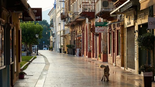 Old town of Nauplion, deserted street with morning sun and a dog in front of historic shops,