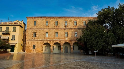 Old town of Nauplion, historic brick building with round arches in front of a paved square with