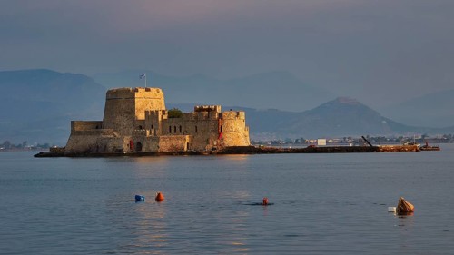Bourtzi island fortress, old fortress on an island in the calm sea, surrounded by buoys and
