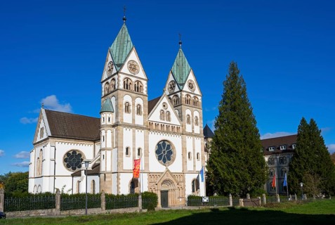 Impressive church with double towers against a blue sky and surrounded by trees, Bonifatiuskloster,