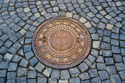 Round metal manhole cover on paved ground with interesting structure, manhole cover, Hünfeld,