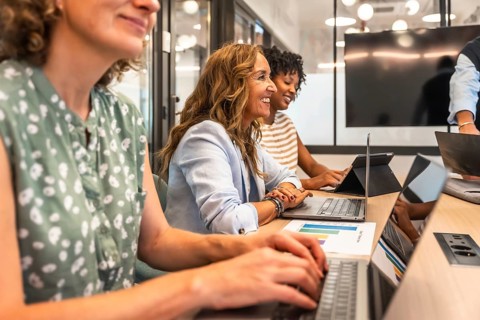 Diverse group of smiling businesswomen collaborating and engaging in productive work during a team