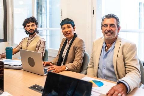 Diverse business colleagues working together around a table in a bright coworking office, smiling