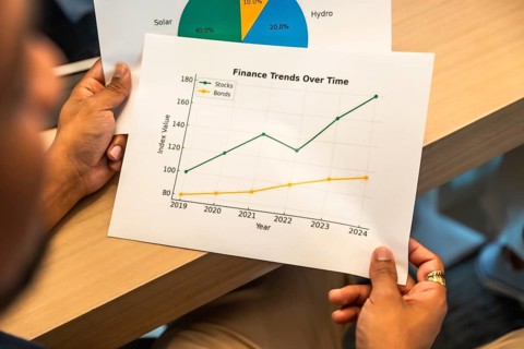 Person reviewing printed financial report showing investment trends, stock and bond performance