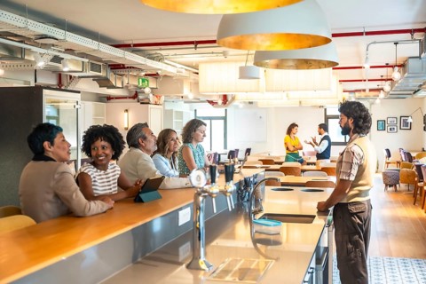 Diverse business colleagues enjoying a casual conversation at the counter of a modern coworking
