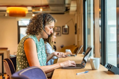 Women concentrating on their work using laptops and headsets in a modern coworking office,